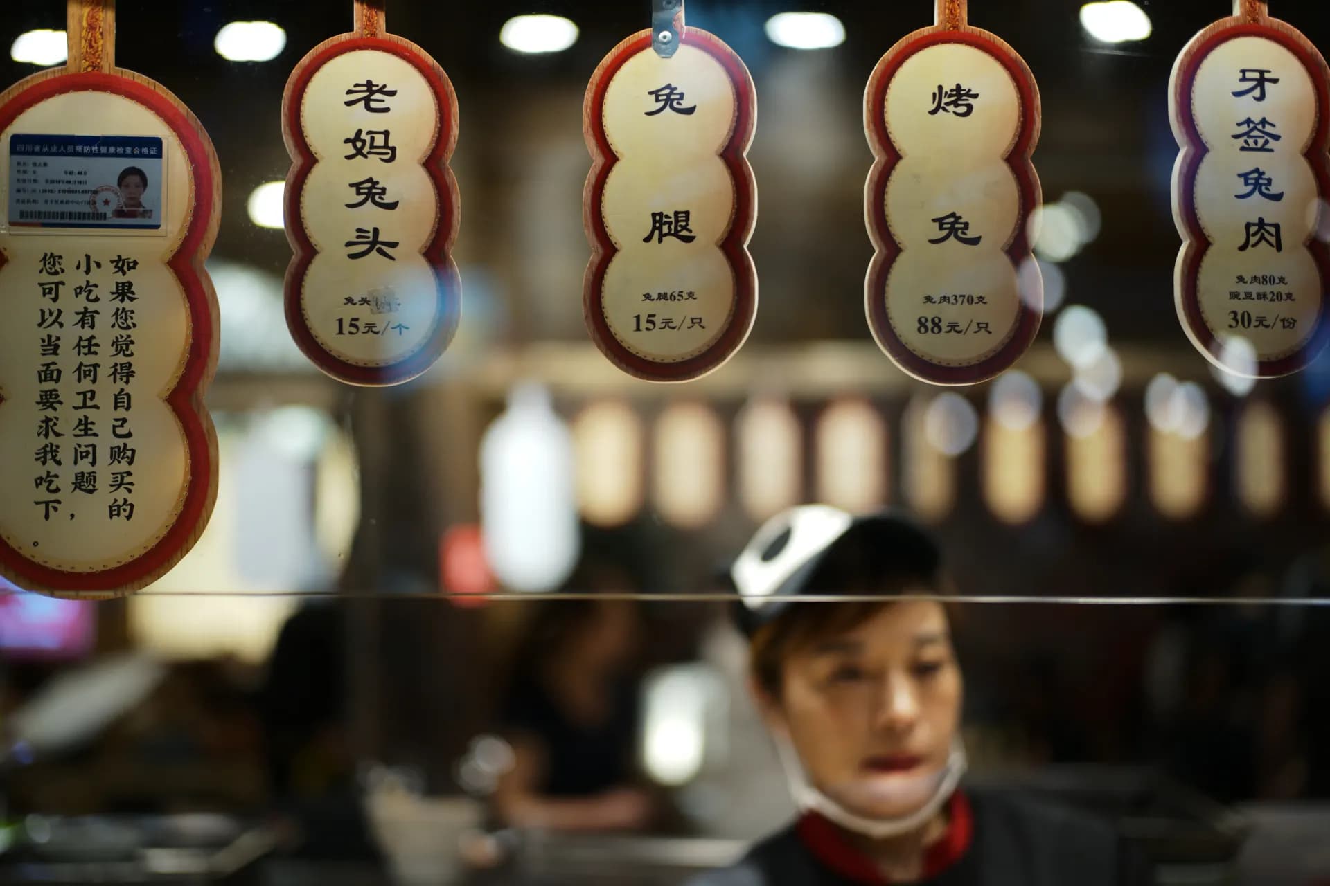 Asian food stall with hanging signs and blurred worker