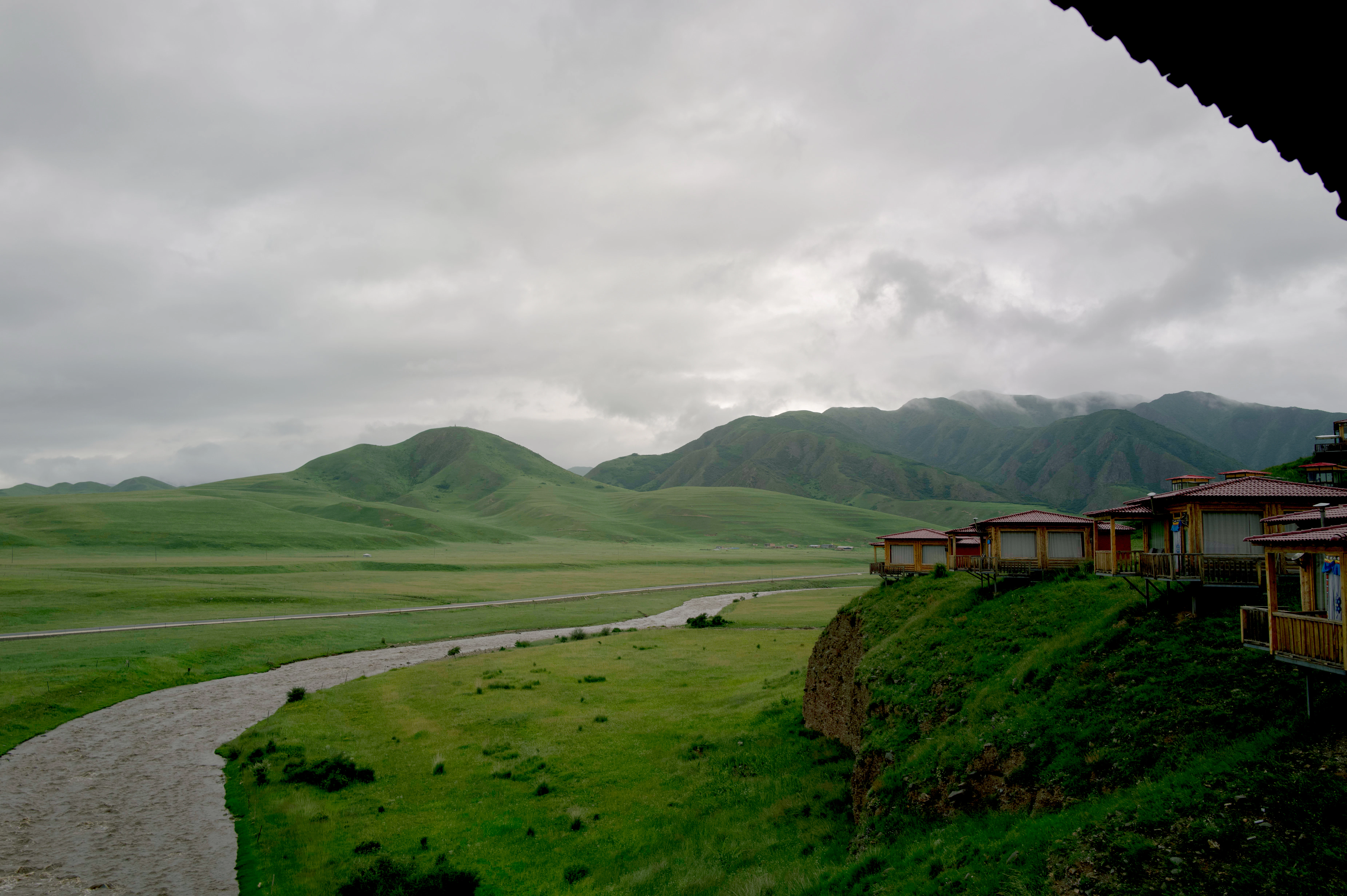 Green rolling hills with a river and cabins
